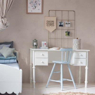 Quarto com mesa branca e cadeira azul claro ao lado de cama e decoração na parede