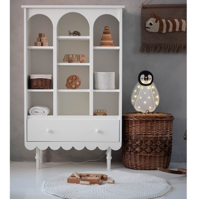 Estante branca com brinquedos de madeira e lâmpada pinguim decorativa ao lado