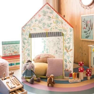 Espelho com moldura em forma de casa e brinquedos em cima da mesa