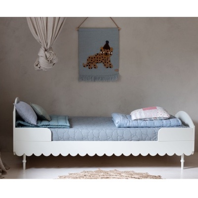 Cama infantil branca com roupa azul e tapeçaria de cão azul na parede cinza