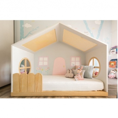 Cama infantil em formato de casa com almofadas decorativas num quarto claro