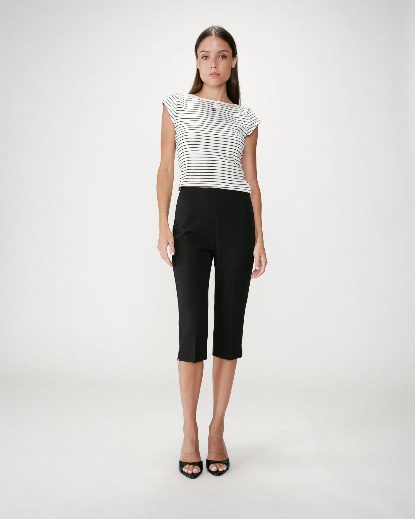 Where Capri Trousers Mulher com blusa branca com riscas pretas e calças pretas até meio da perna