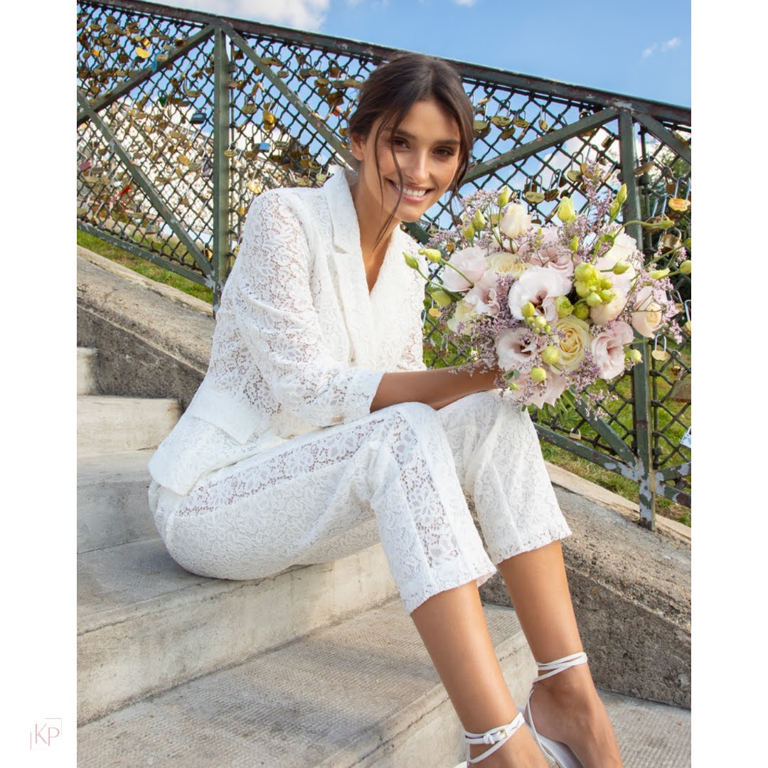 Sango Lace Trousers Conjunto branco de renda feminino com bouquet de flores pastel, mulher sentada em escadaria ao ar livre