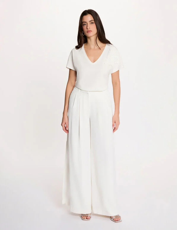 Poma Wide Leg Trousers Mulher a usar conjunto branco com blusa de manga curta e calças largas.