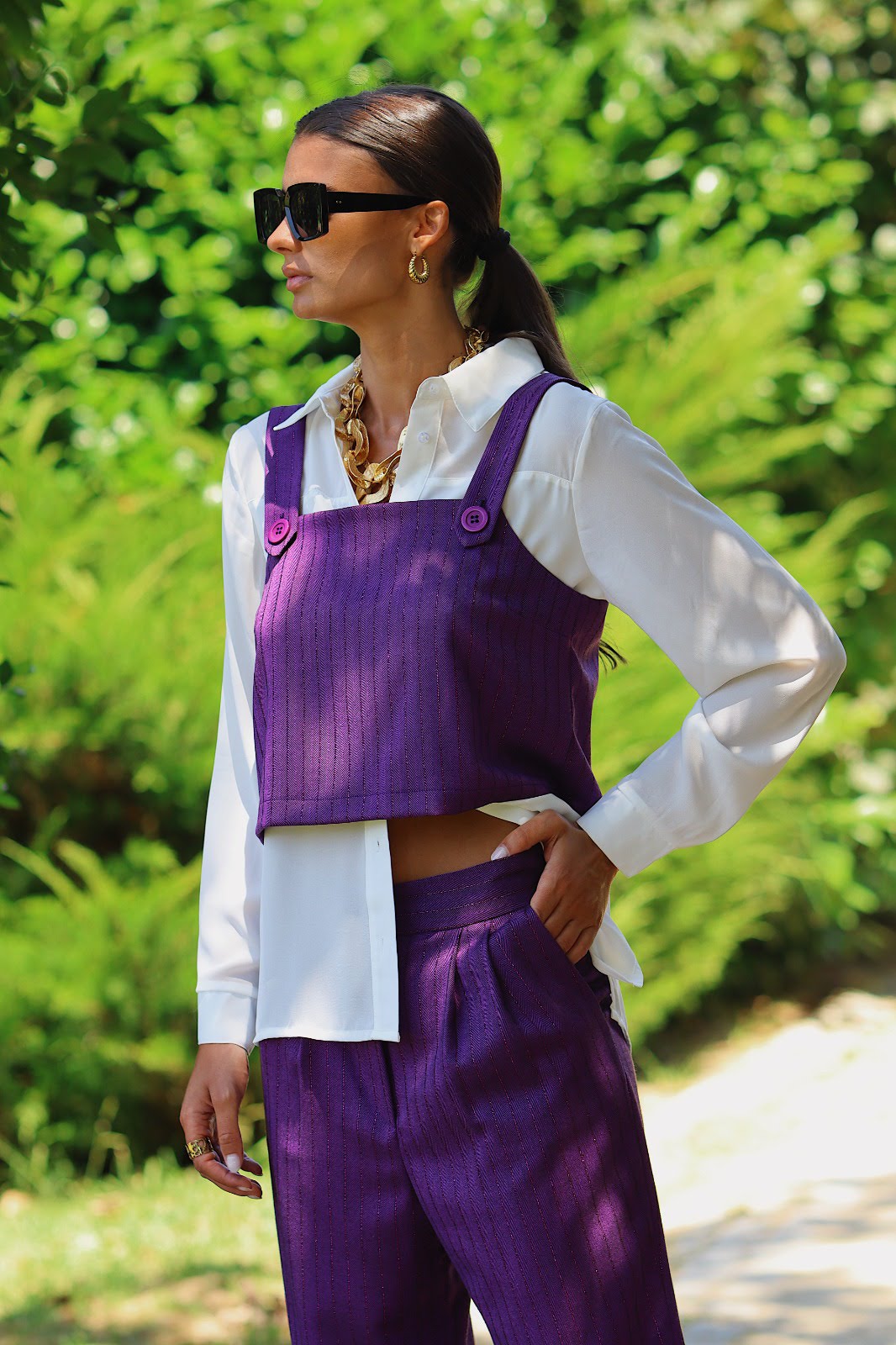 lur top Mulher vestindo conjunto roxo com camisa branca e acessórios dourados ao ar livre