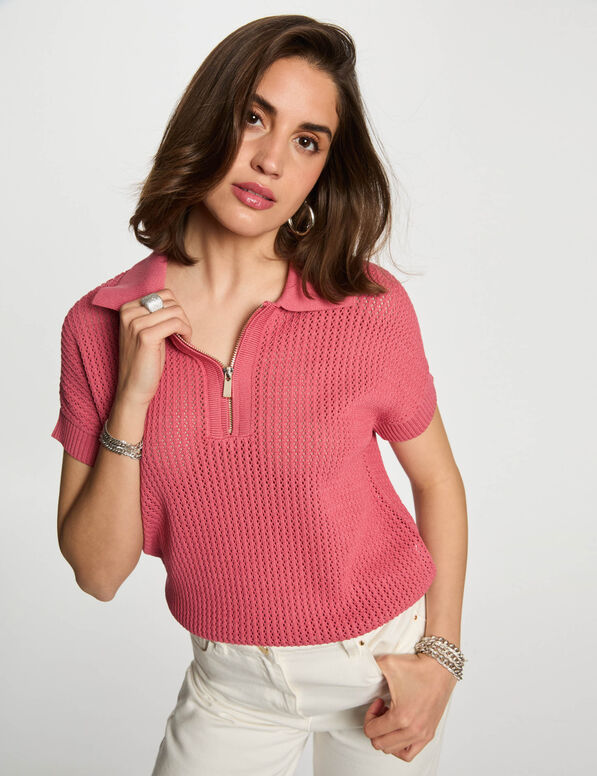 Laos Polo Camisola rosa de malha com gola e fecho, calças brancas e acessórios prateados.
