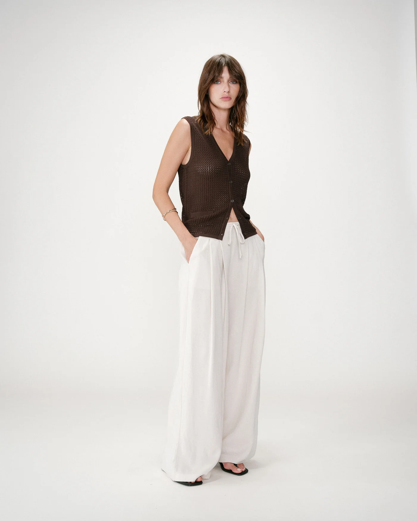 Wally Linen Wide Trousers Mulher vestindo colete castanho de malha e calças largas brancas
