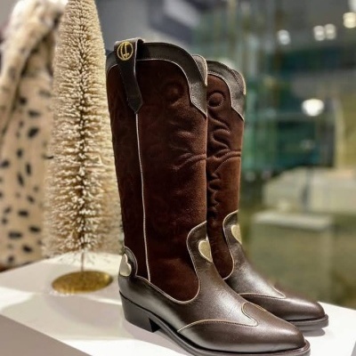 Botas castanhas de cano alto em exposição com árvore decorativa ao lado