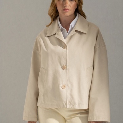 Mulher com casaco bege claro de botões e calças claras