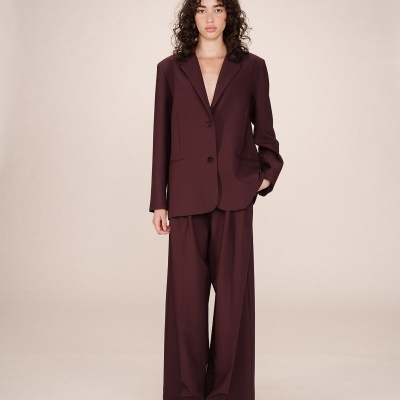 Conjunto de senhora bordô com blazer e calças largas em fundo neutro
