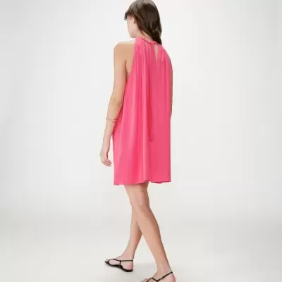 Vestido curto cor-de-rosa feminino com alças finas e costas abertas, sandálias pretas.