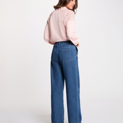 Mulher de costas com calças de ganga azuis largas e blusa rosa clara com detalhes rendados nos ombros