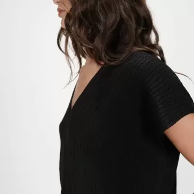 Mulher com camisola preta de malha canelada e decote em V