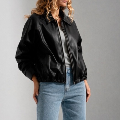 Casaco preto de pele sintética com fecho, com modelo vestindo jeans azuis claros e camisola cinza