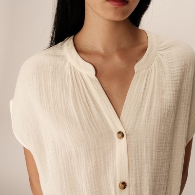 Blusa branca com botões castanhos e textura riscada