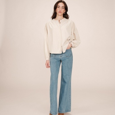 Mulher a vestir blusa creme de mangas bufantes e jeans azul claro largo