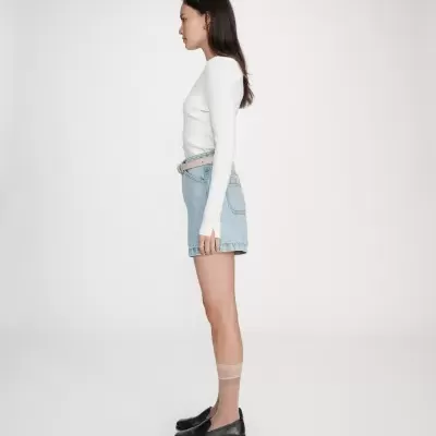 Mulher com camisola branca e mini saia de ganga azul