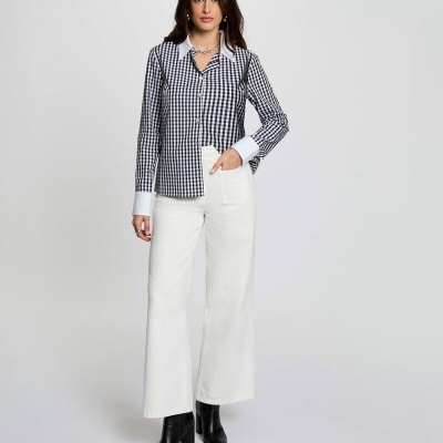 Mulher com camisa xadrez preto e branco, calças brancas e botas pretas