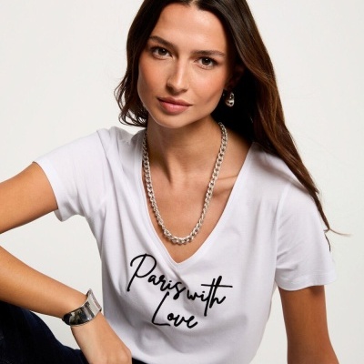 Mulher a usar t-shirt branca com texto 'Paris with Love' e acessórios