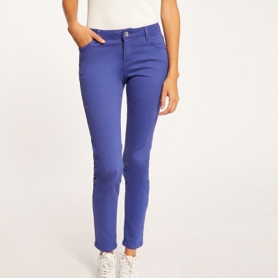 Calças azuis justas femininas com t-shirt branca e ténis brancos num fundo claro