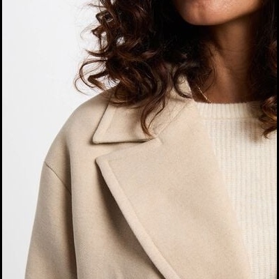 Casaco bege com gola ampla em lapela usado por mulher