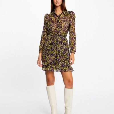 Modelo com vestido curto floral amarelo e roxo e botas brancas