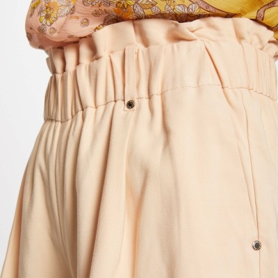 Calças bege com cintura elástica e blusa amarela floral