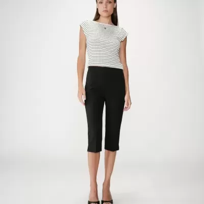 Mulher com blusa branca com riscas pretas e calças pretas até meio da perna