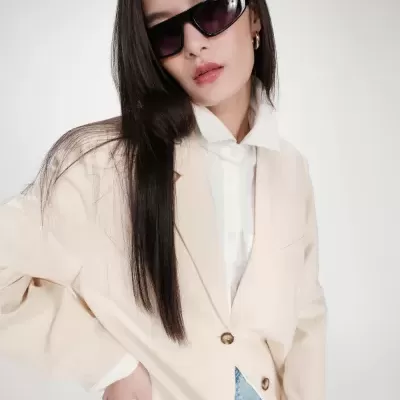 Mulher com óculos de sol pretos e casaco bege