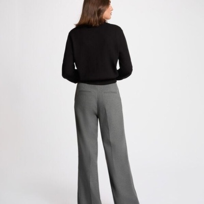 Mulher de costas com camisola preta e calças largas cinza