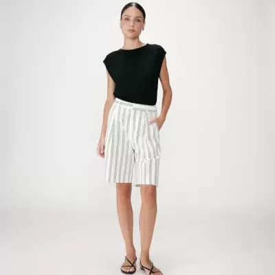 Mulher com top preto e calções brancos às riscas verticais pretas com sandálias pretas