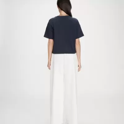 Pessoa de costas com t-shirt azul escura e calças largas brancas