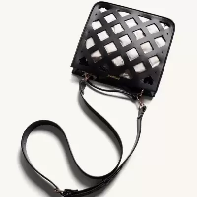 Mala transversal preta com padrão recortado e alça ajustável