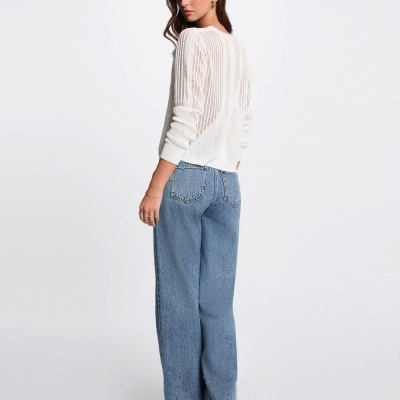 Mulher de costas com camisola branca de malha e jeans azuis