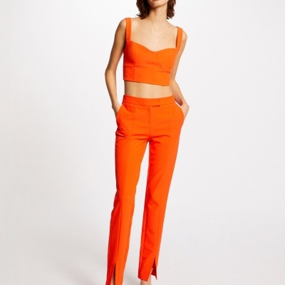 Mulher a usar conjunto laranja com top cropped e calças com fendas na bainha