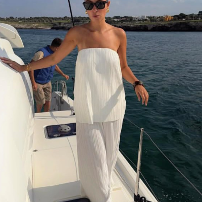 Mulher de vestido branco longo numa embarcação de vela