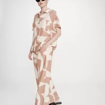 Conjunto de roupa com padrão geométrico bege e castanho claro com óculos escuros e sapatos pretos