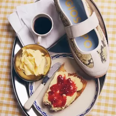 Sapatilha Gioseppo com padrão pele de cobra sobre tabuleiro com pequeno-almoço