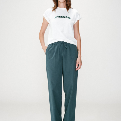 Modelo com t-shirt branca pistacchio e calças azuis largas
