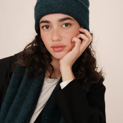 Mulher a usar gorro e cachecol azuis de malha com textura felpuda e casaco preto