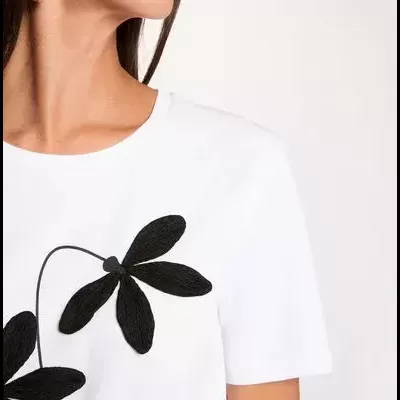 T-shirt branca com bordado preto de flor em fundo branco
