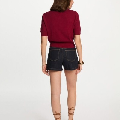 Mulher de costas com camisola vermelha, calções de ganga e sandálias castanhas