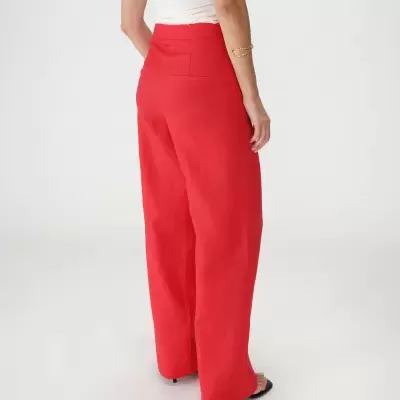 Calças vermelhas largas em tecido liso, top branco e pulseira dourada com fundo branco