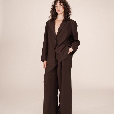 Conjunto formal castanho escuro de mulher com blazer e calças largas em fundo claro
