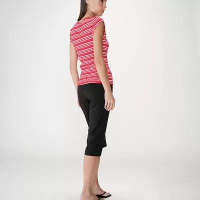 Mulher com t-shirt às riscas vermelhas e brancas, calças pretas capri e sandálias pretas.