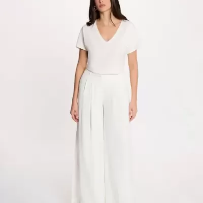 Mulher a usar conjunto branco com blusa de manga curta e calças largas.