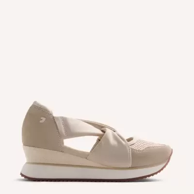 Tênis bege com cunha e design recortado sobre fundo claro