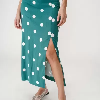Saia comprida verde com bolinhas brancas e fenda lateral.