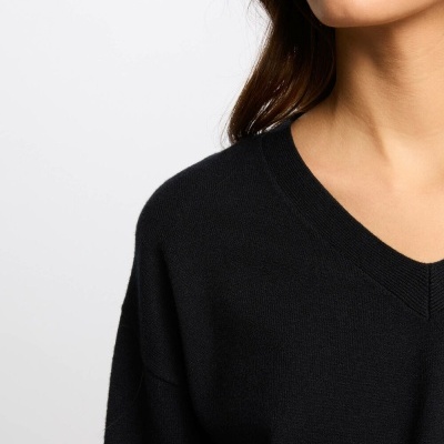 Camisola preta de malha com decote em V usada por mulher