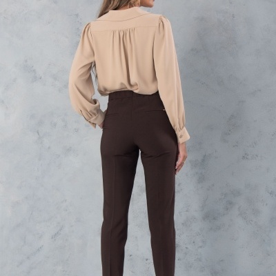 Pessoa de costas com camisa bege e calças castanhas escuras